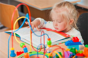A child reading a book beside sensory toys